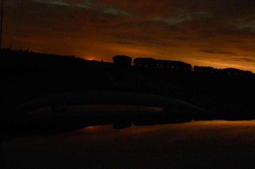 Faint aurora above a dark cloudy sky, with an orange glow on the horizon.