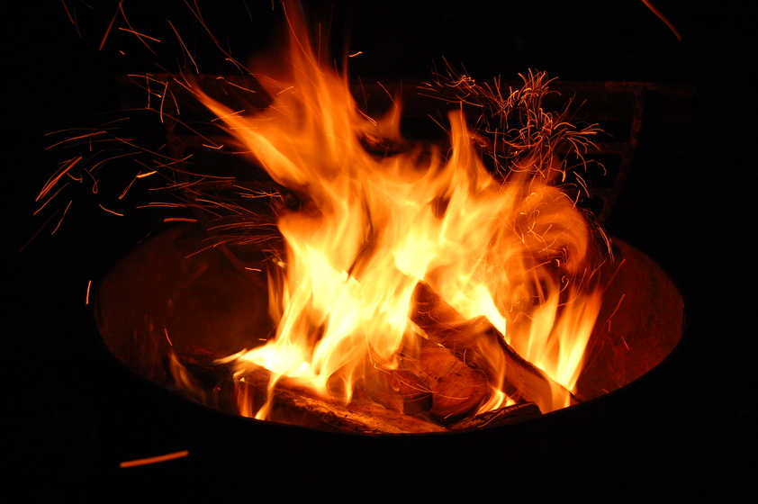 A campfire burns in a contained metal fire pit.