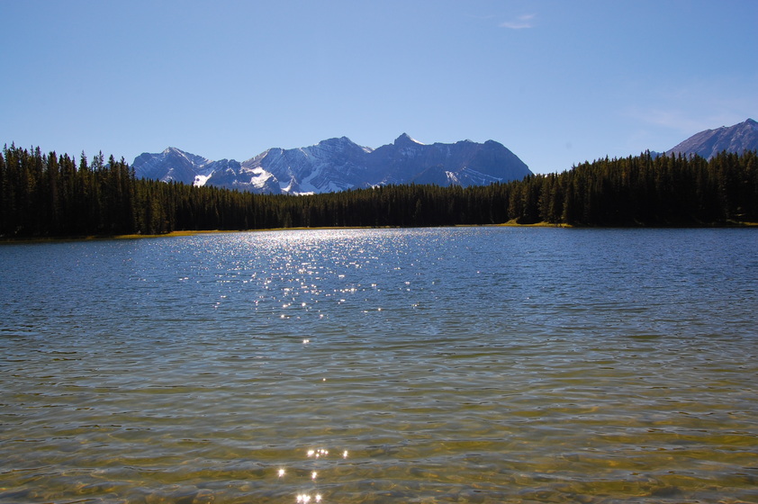 A scenic view of a lake reflecting the sky in a peaceful forest setting.