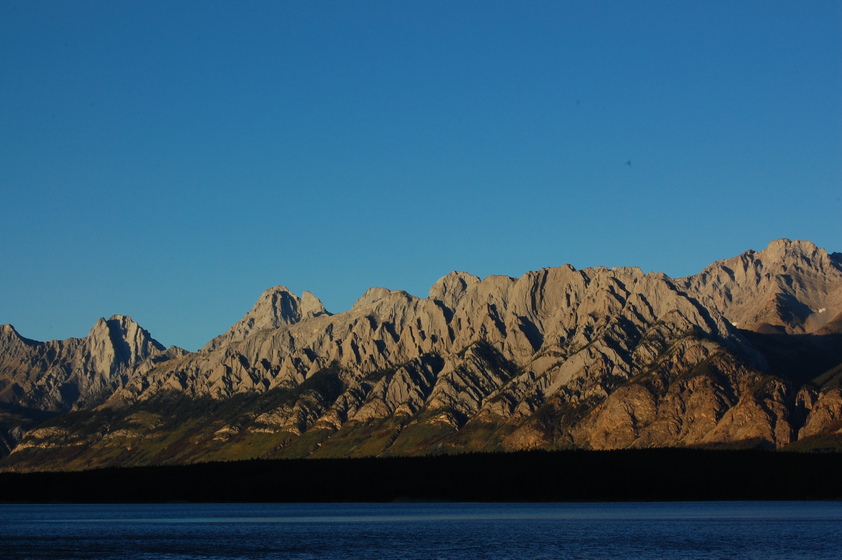 A peaceful mountain landscape with a lake in the foreground.