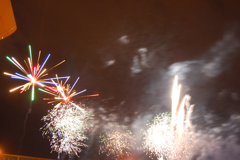 A group of fireworks exploding in a dark night sky. The fireworks are colorful and bright, with streaks of red, green, gold, and blue.