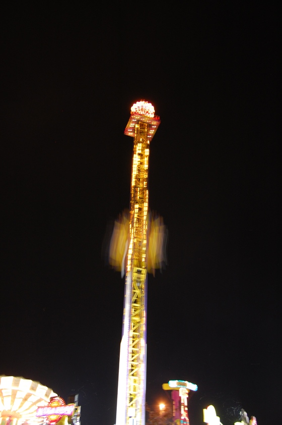A close-up photo of a lit-up carnival ride at night.