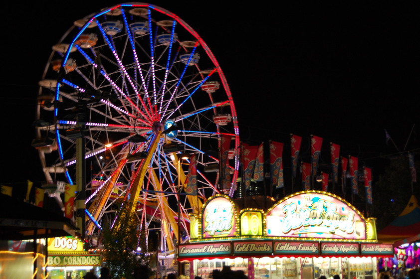 A ferris wheel at a fairground with text listing fairground treats.