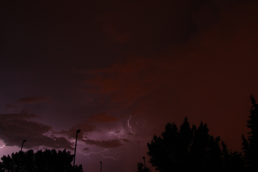 A nighttime sky with scattered clouds and lightning bolts illuminating the darkened landscape.