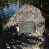 A rock with a plaque attached to it. The plaque reads: IN APPRECIATION OF LAWRENCE GRASSI 1890 - 1980 MASTER TRAILMAKER HE SOUGHT NEW PATHS, MADE ROUGH PLACES SMOOT, POINTED THE WAY TO HIGHER LEVELS AND LOFTIER ACHIEVEMENTS
