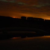 Faint aurora above a dark cloudy sky, with an orange glow on the horizon.