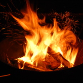 A campfire burns in a contained metal fire pit.
