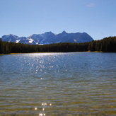 A scenic view of a lake reflecting the sky in a peaceful forest setting.