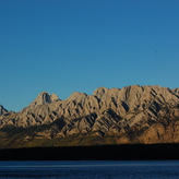 A peaceful mountain landscape with a lake in the foreground.