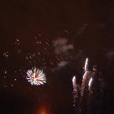 Bright bursts of red, green, gold, and blue light fill the dark night sky.