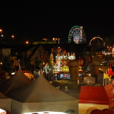 A photo of the Calgary Stampede at night, with a brightly lit Ferris wheel in the background.