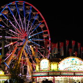 A ferris wheel at a fairground with text listing fairground treats.