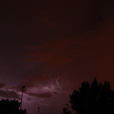A nighttime sky with scattered clouds and lightning bolts illuminating the darkened landscape.